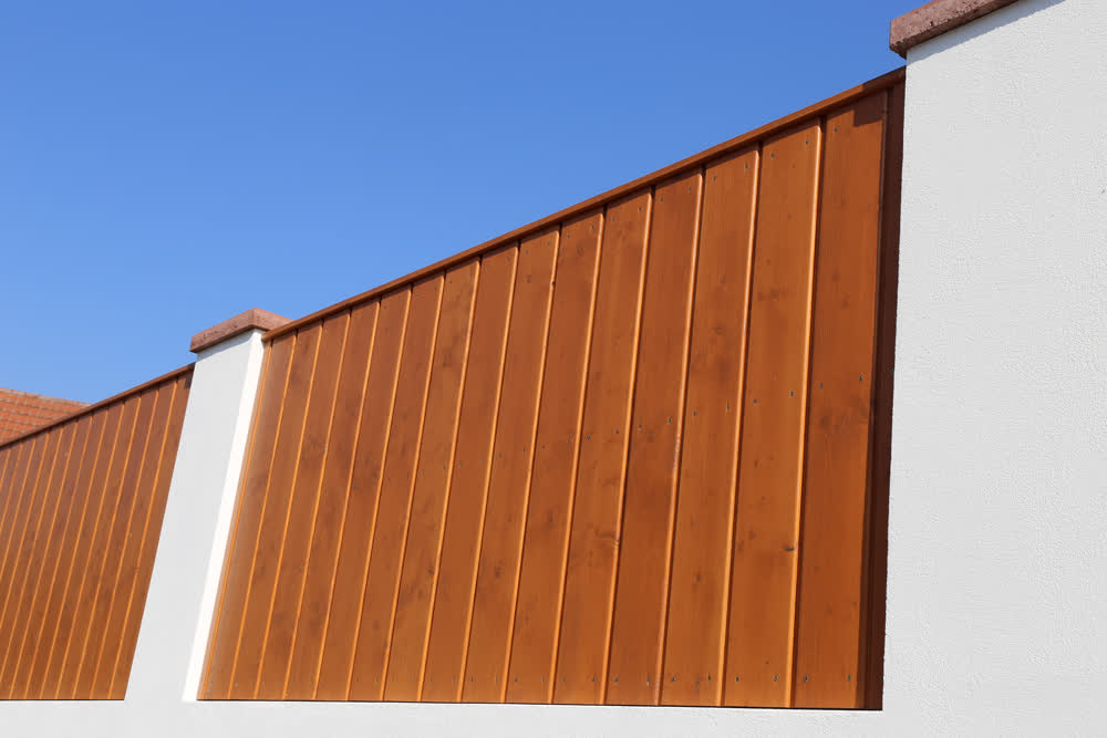 Wooden fence with spaced white pillars and plank cap